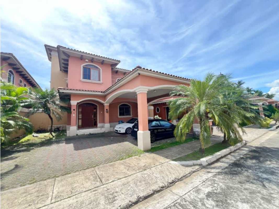 Exterior of two-story Mediterranean style house with peach facade, covered carport and palm trees in Costa Sur Panama City