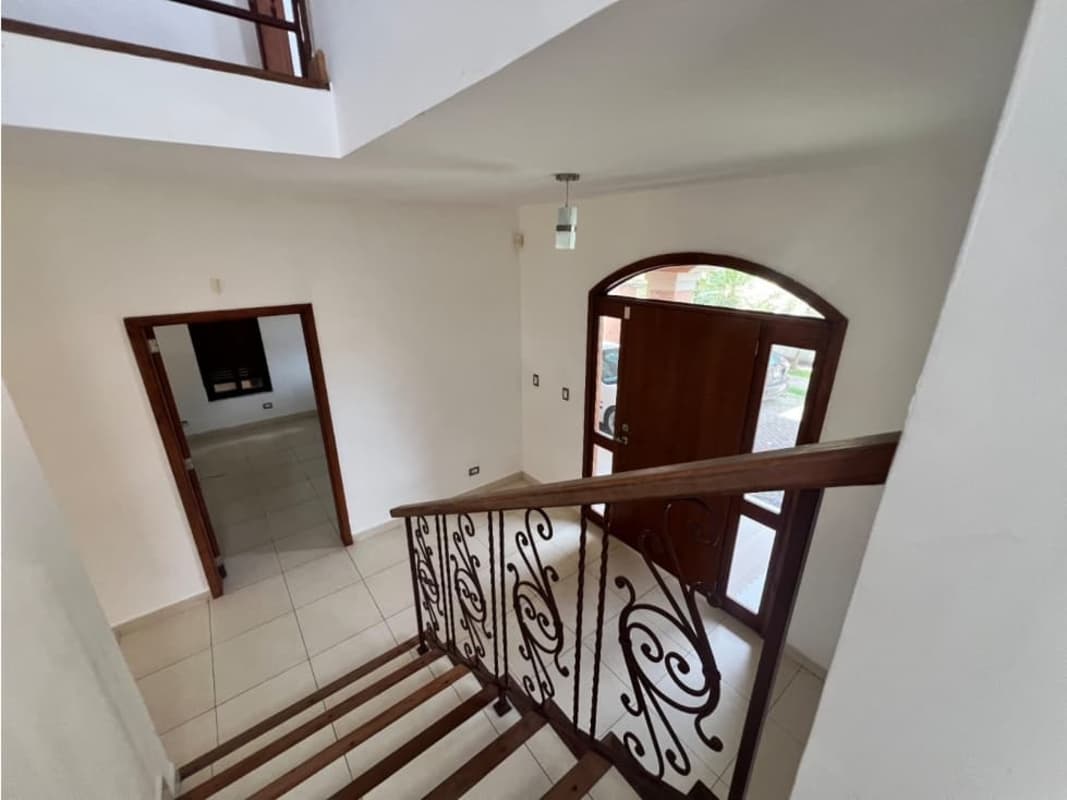 Entryway with decorative iron staircase, wood door and ceramic tile floors at luxury home in Costa Sur Panama