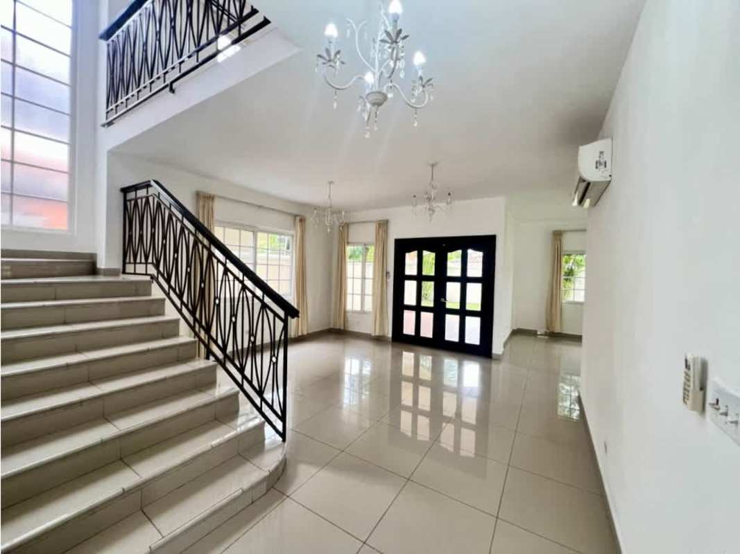 Open-plan living area with tiled floor, windows, black staircase railing in Villa Valencia Costa Sur Panama City