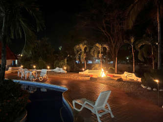 Tropical night patio pool fire pit loungers palm trees at Gorgona beach house rental
