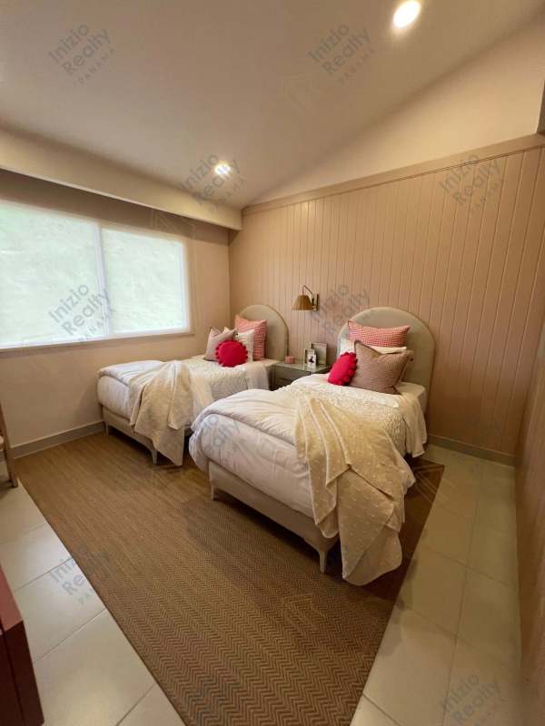 Bedroom with two beds, beige accent wall and big window in Brisas del Golf townhouse Panama