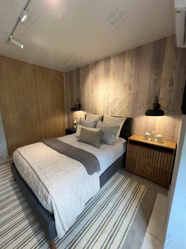 Master bedroom with wood accent wall, walk-in closet, and modern decor in Brisas del Golf Panama