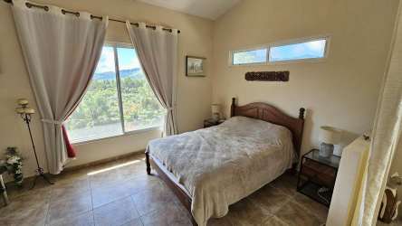 Bedroom with large window showing lush garden and mountains in Altos del María