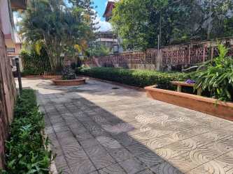 Two-story pink house with gated fence, balcony, tropical landscaping Margarita Colón Panama