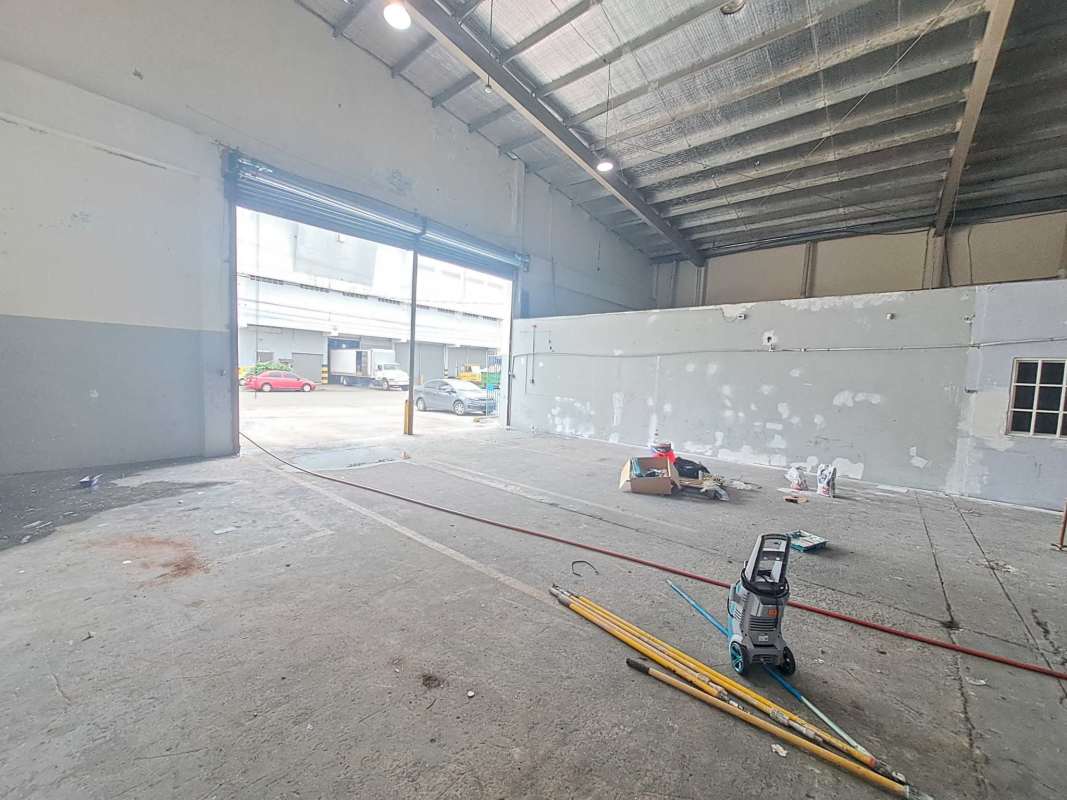 Warehouse interior with exposed roof trusses, lighting, and roller door Costa del Este