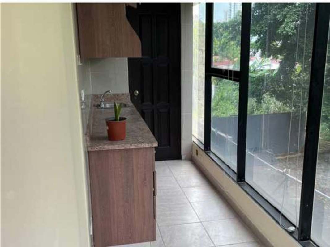 Compact kitchenette with marble counter, sink and large windows inside Panama office