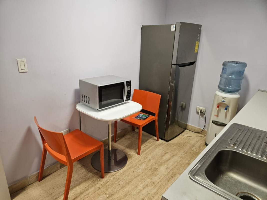 Small kitchenette with fridge, microwave and dining chairs in Torre Las Américas office Panama City