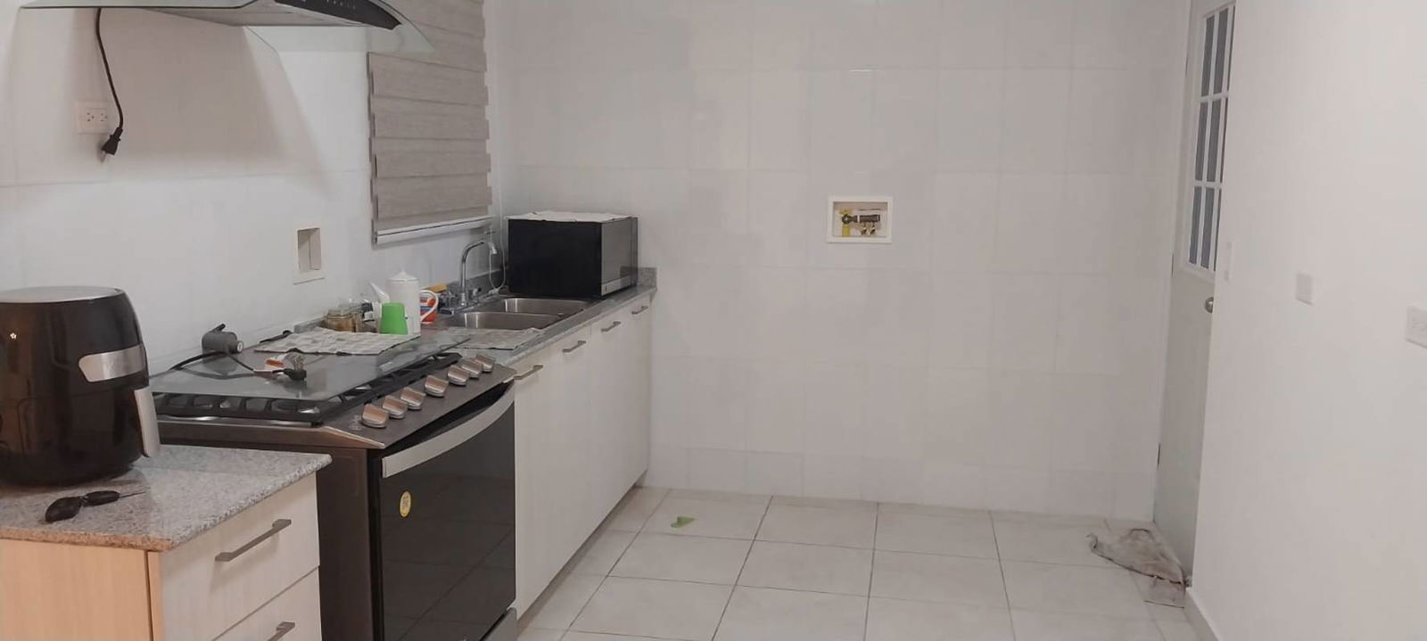Empty living room with tiled floors, white walls and blinds at Cumbres del Lago Panama City
