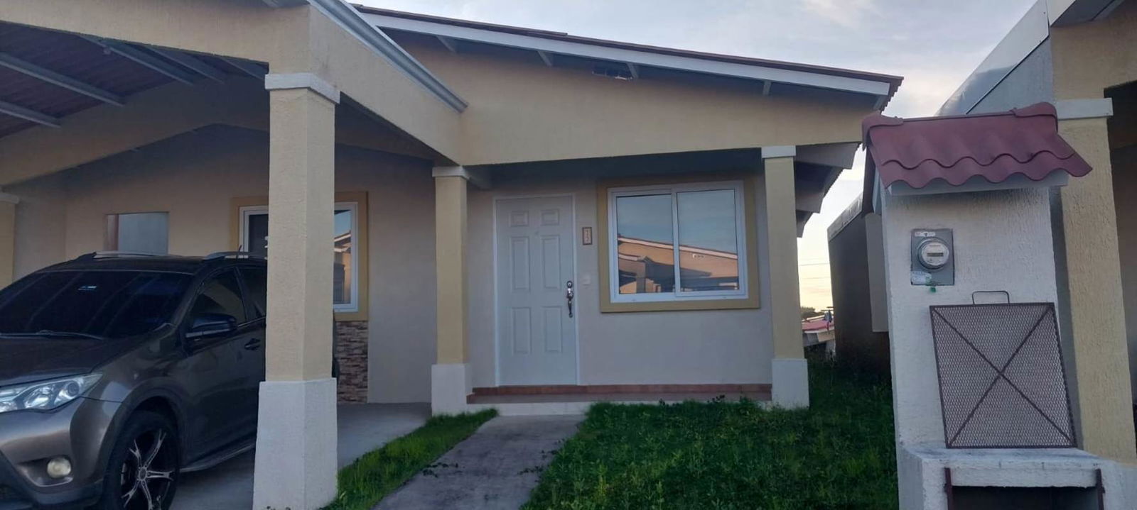 Single-story house exterior with covered parking, front yard, beige walls in Cumbres del Lago Panama City