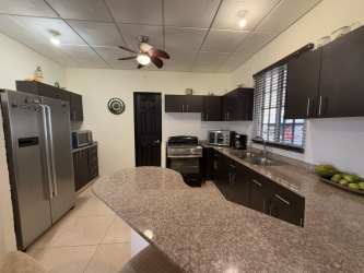 Spacious living room with tray ceiling, ceiling fan, and wicker sofas in Brisas del Sur house Panama