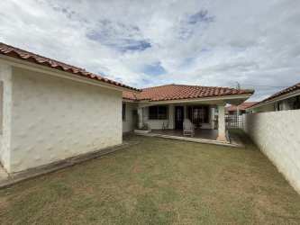 Red tiled roof, covered patio with stucco walls and grass yard in Chitré Panama