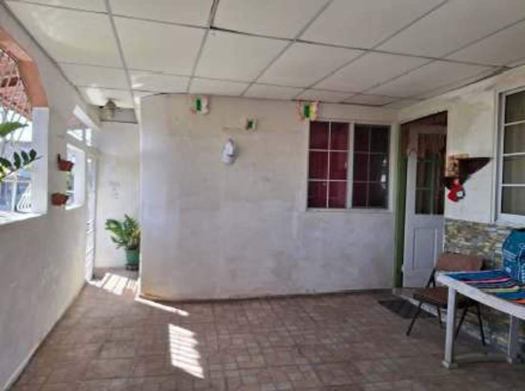 Enclosed porch with tiled floors plants grill windows in Panama house