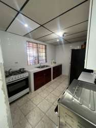 Kitchen with tiled walls, gray patterned floor, gas stove, refrigerator in Panama house for sale