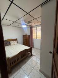 Simple tiled bedroom with window, wooden furniture, traditional style house for sale Arraiján Panama