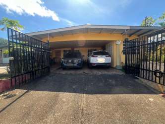 Exterior with yellow facade, covered parking, security gate house for sale in La Arboleda Panama