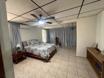 Bedroom with ceiling fan, tiled floor, large curtained window in family house in La Arboleda Panama