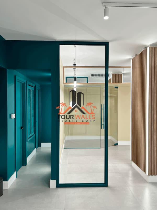 Hallway with glass door, teal accent wall, and wood accents in PH Ejecutivo tower Marbella Panama