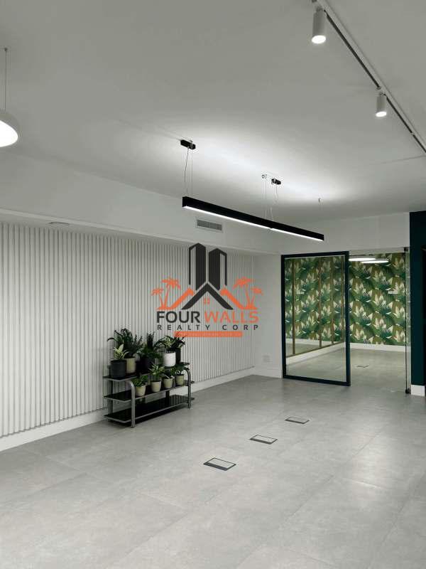 Modern minimalist office lounge with tropical wallpaper, indoor plants, and pendant lighting in Marbella, Panama