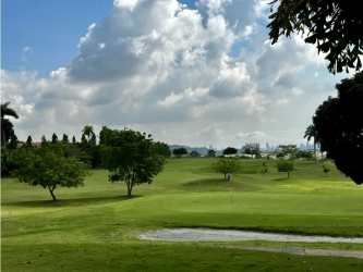 Wide view of green golf course with trees and Panama City skyline from Tucan Country Club