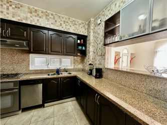 Kitchen with granite countertop, appliances, and dark cabinets in Tucan Country Club apartment Panama