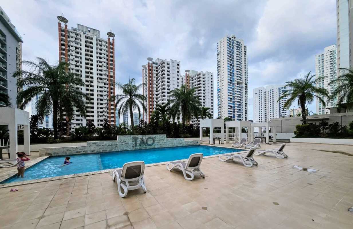 Swimming pool surrounded by lounge chairs and palm trees at PH Tao Panama City