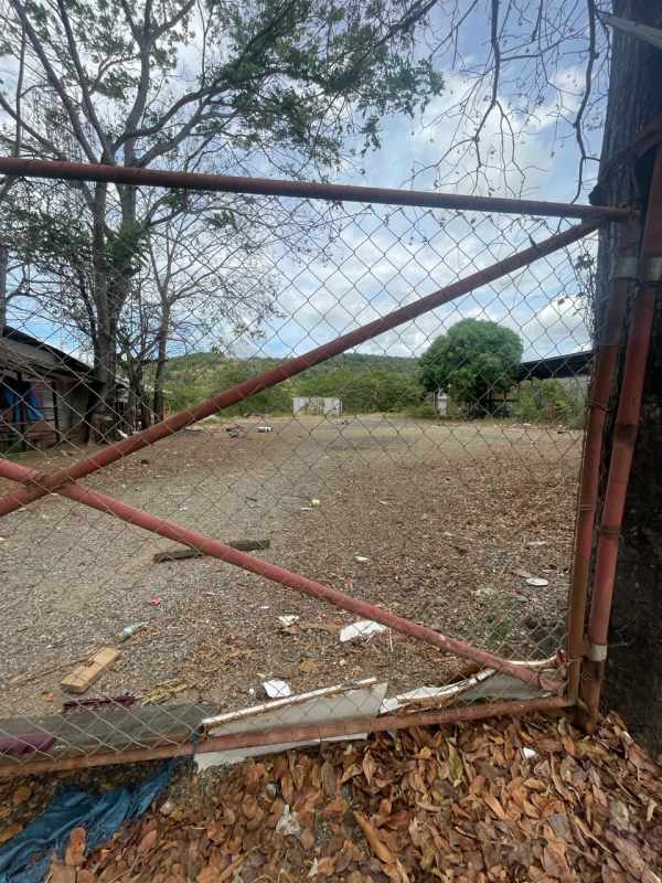 Spacious vacant flat land fenced with minor debris and distant outbuildings Tocumen Panama