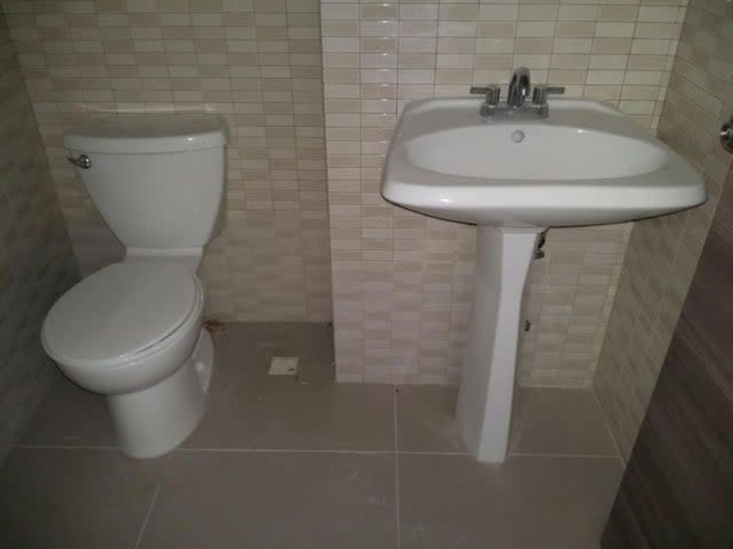 Compact white bathroom with pedestal sink and toilet at retail unit Terrazas de Albrook