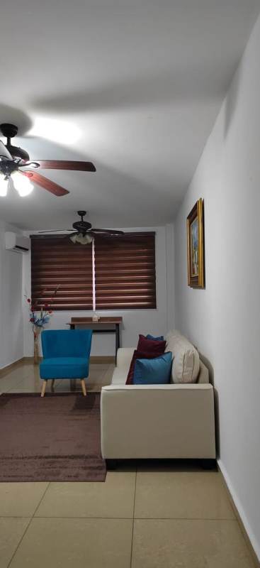 Living area with AC unit, ceiling fans, blue accent chair and decorative wall art PH Urbis Tower Panama City