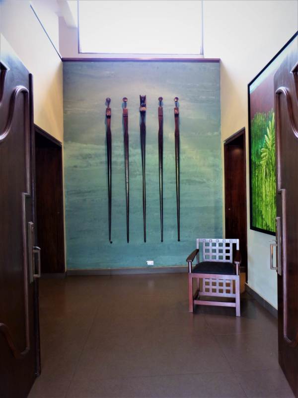 Enclosed patio with wicker seating, glass dining table, wood ceiling and garden view in Dos Mares house Panama