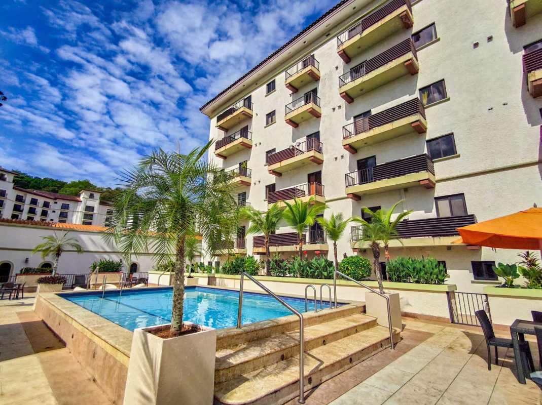 Mediterranean apartment complex exterior with central courtyard pool surrounded by palm trees and balconies