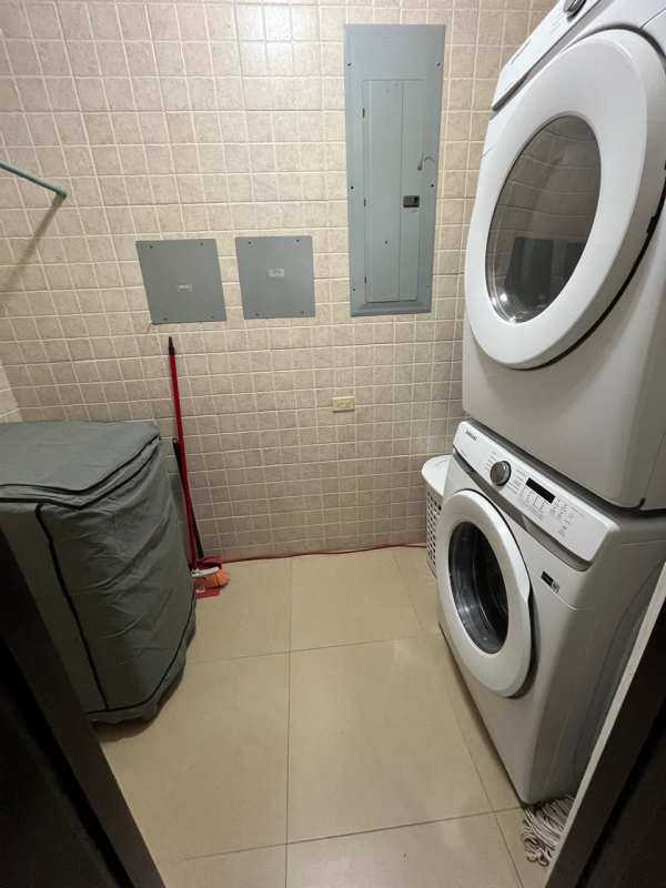 Compact laundry with stacked washer dryer beige tile wall at Embassy Village Clayton Panama