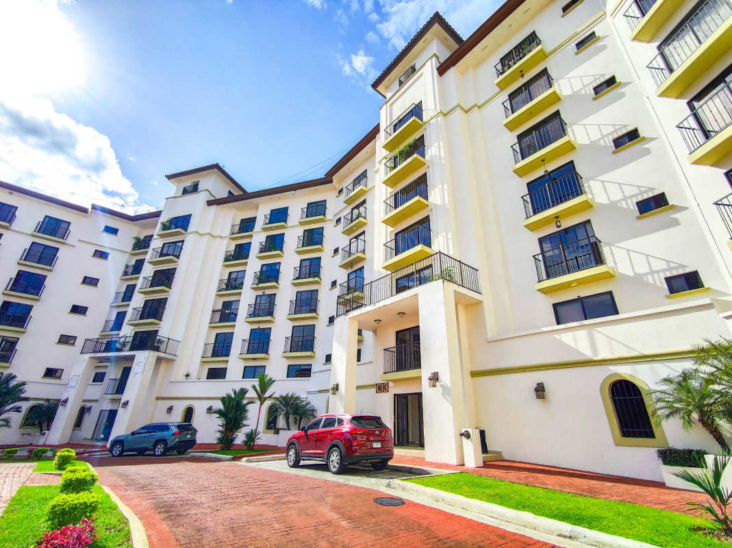 Multi-story Mediterranean apartment with balconies and lush landscaping at Embassy Village Clayton