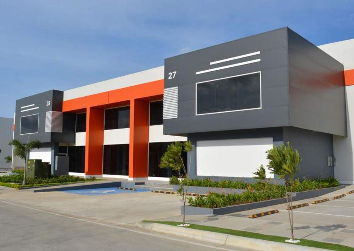 Facade of new industrial warehouse with glass panels, orange accents, 7 parking spots at Free Zone 24 de Diciembre Panama