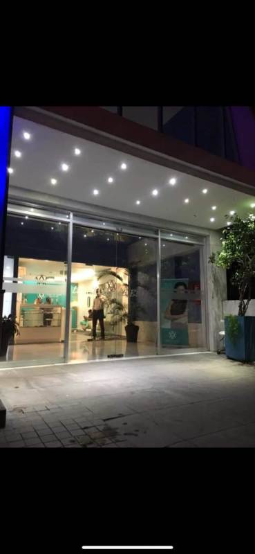 Modern blue glass office tower facade with illuminated signage at night El Carmen Panama