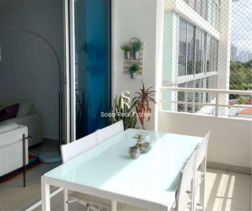 Covered balcony with table, chairs, and potted plants overlooking city Panama
