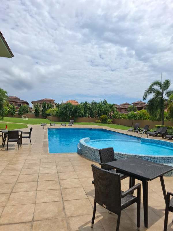 Swimming pool with deck chairs surrounded by garden landscaping in Costa Sur Panama