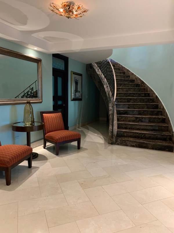 Grand foyer with curved marble staircase and upscale finishes in Altos del Golf penthouse Panama City