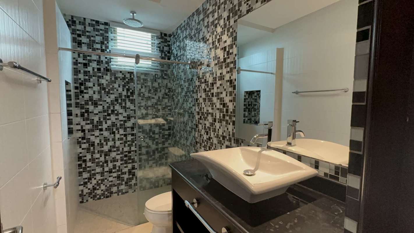 Luxury bathroom with blue mosaic tiles, vessel sink, and glass shower in penthouse Altos del Golf Panama
