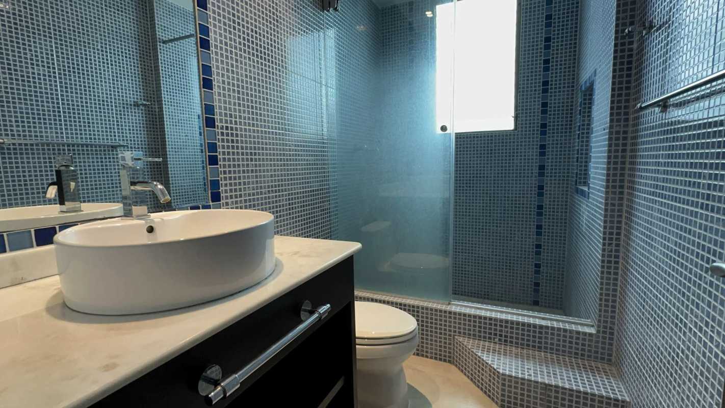 Bathroom with blue mosaic tiles, vessel sink and glass shower in penthouse Altos del Golf Panama