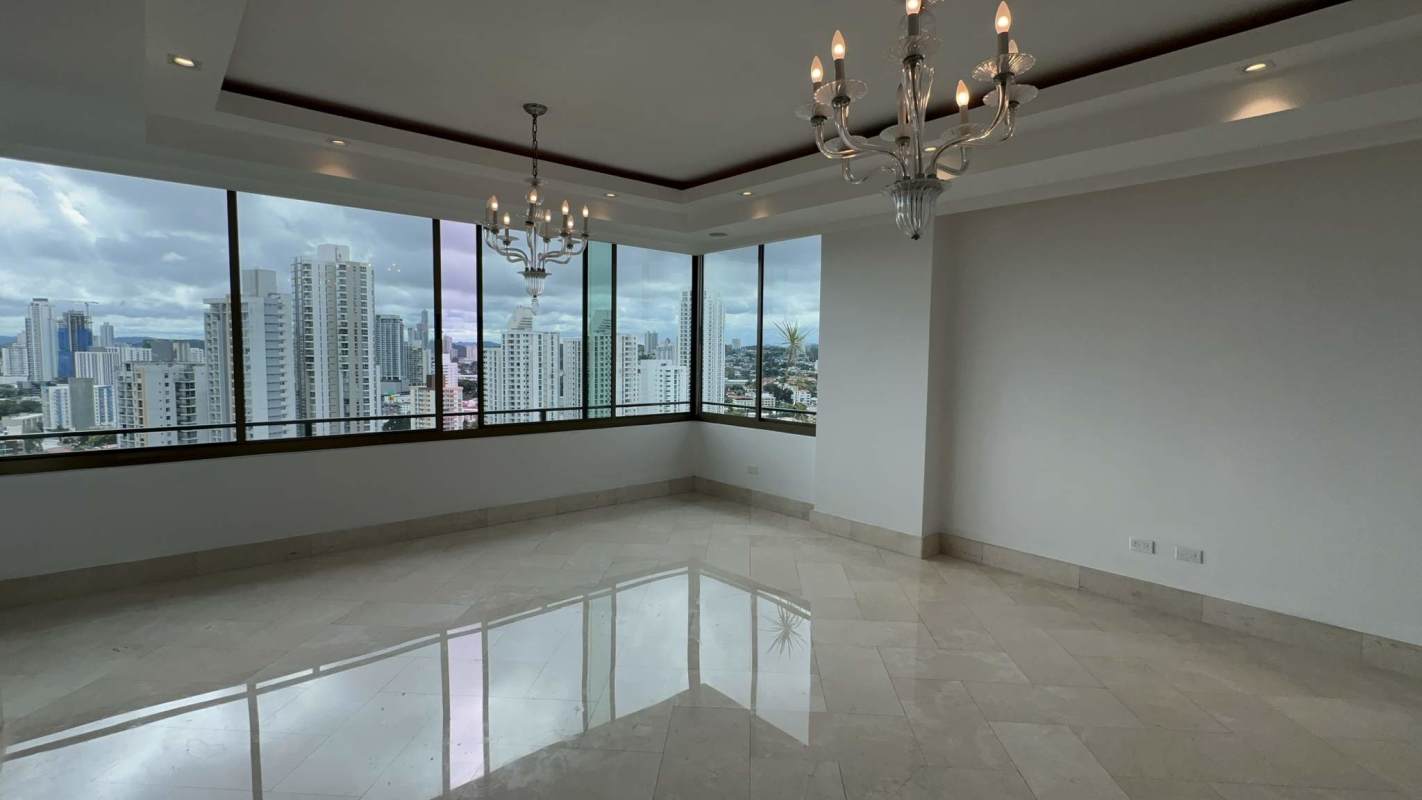 Corner living room with floor-to-ceiling windows and panoramic city skyline view in Altos del Golf penthouse Panama City