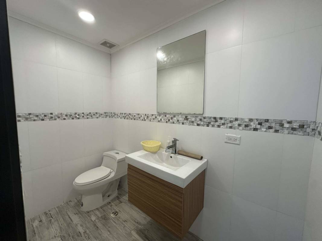 Office bathroom with wood vanity, large mirror, modern design