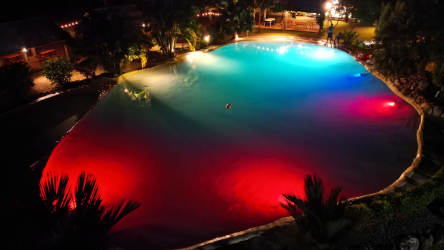Illuminated swimming pool with colored lights and palm trees at night in resort complex Dolega Chiriquí