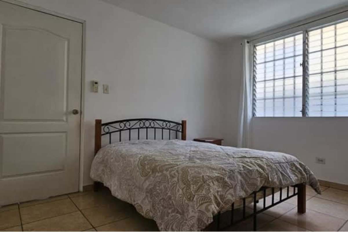 Minimalist bedroom with tile floor, secure window, iron bed frame in Brisas del Occidente Panama