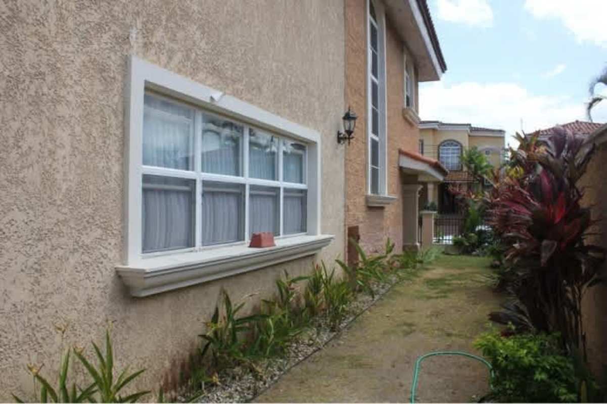 Side facade of Mediterranean-style duplex with stucco walls, windows and landscaped side yard
