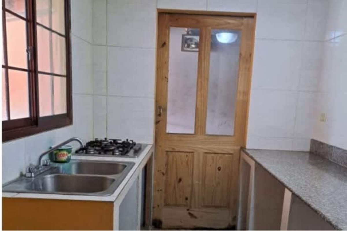 Simple kitchen with granite countertop, gas cooktop, and window in house La Siesta Tocumen Panama