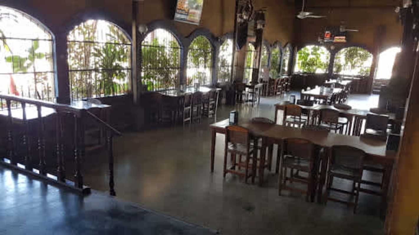 Indoor restaurant with wooden tables chairs and arched windows Juan Díaz Panama