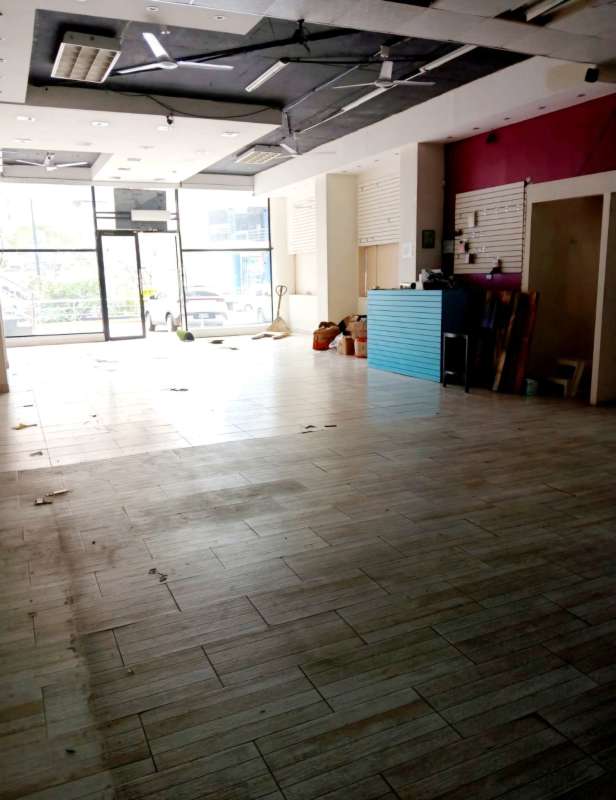 Large open commercial interior with glass entrance, tiled floor, colorful reception counter in Panama