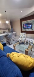 Open living space with blue sofa, marble island kitchen, flat-screen TV in Villa Dora 2 furnished apartment David Panama