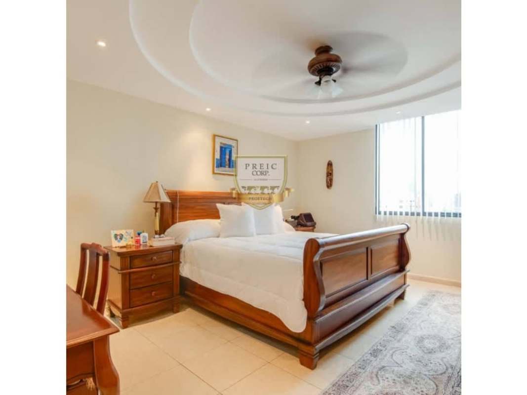 Traditional dining room with glass table, upholstered chairs, large window in PH Plaza Real penthouse