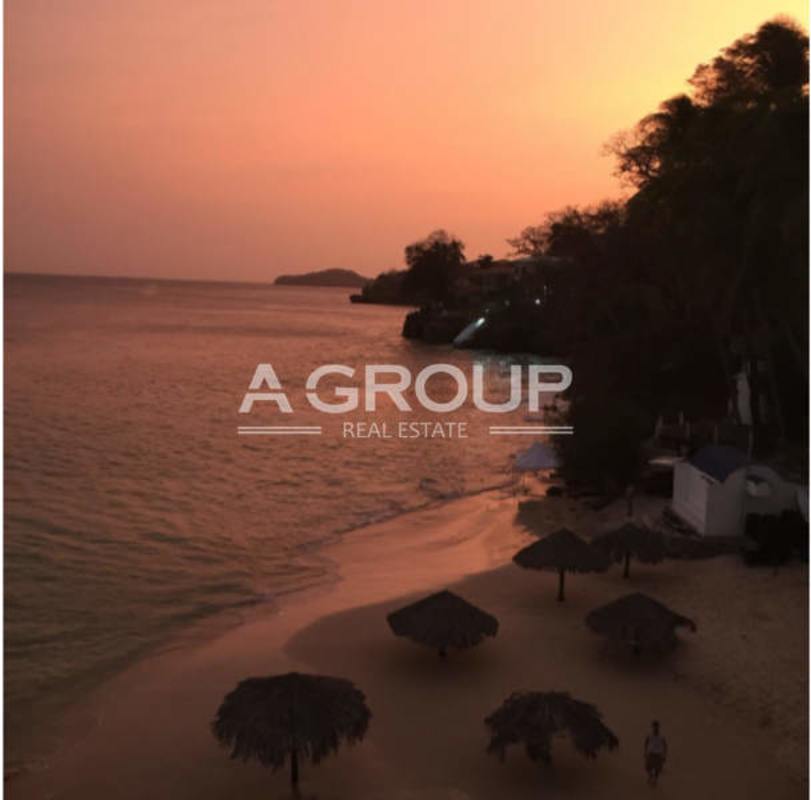 Palapa umbrellas along calm sunset ocean waters at private beach Isla Contadora Panama